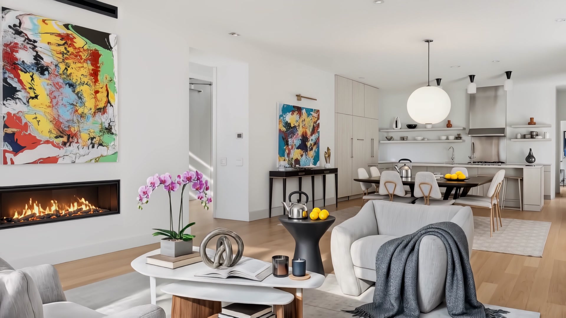Open-plan living room with gas fireplace, contemporary art, and kitchen beyond