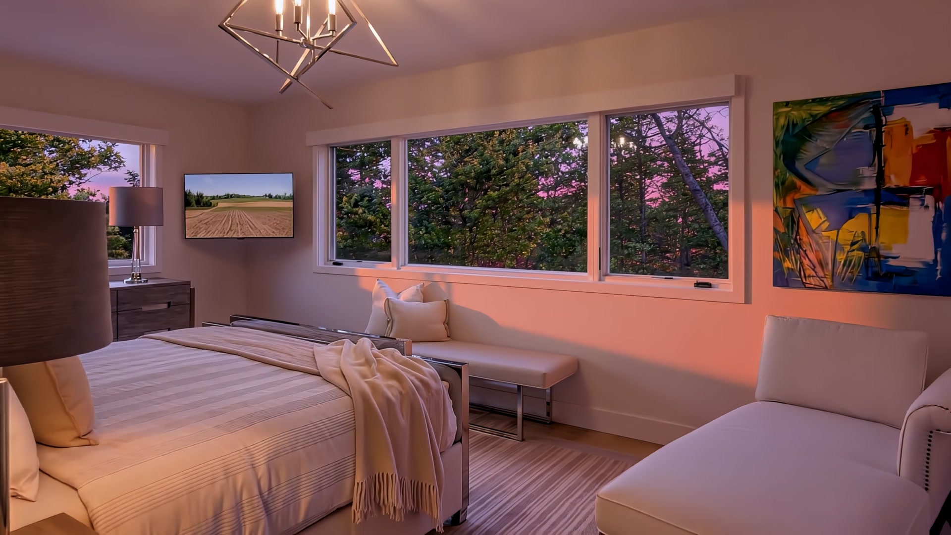 Primary bedroom at sunset with warm light, designer furnishings, and abstract art