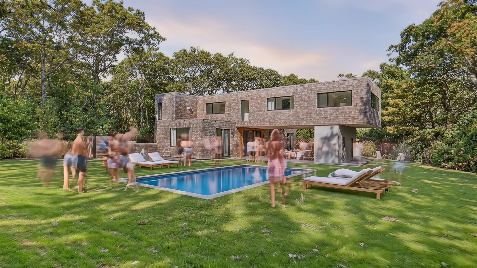 Friends gathering by the pool at dusk with lounge chairs and warm sky